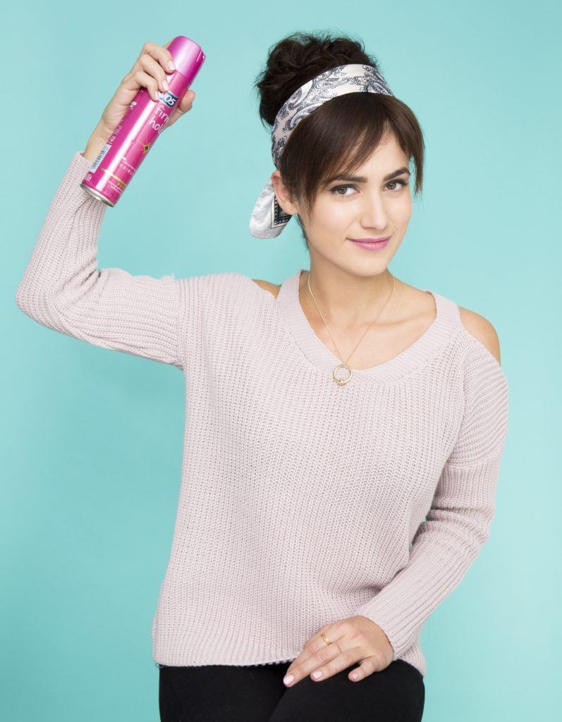 a cute woman with topknot hairstyle spraying her hair