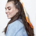 hair updos: brunette model with long brown hair in half-up, half-down bun with headscarf wrapped around the bun wearing denim jacket