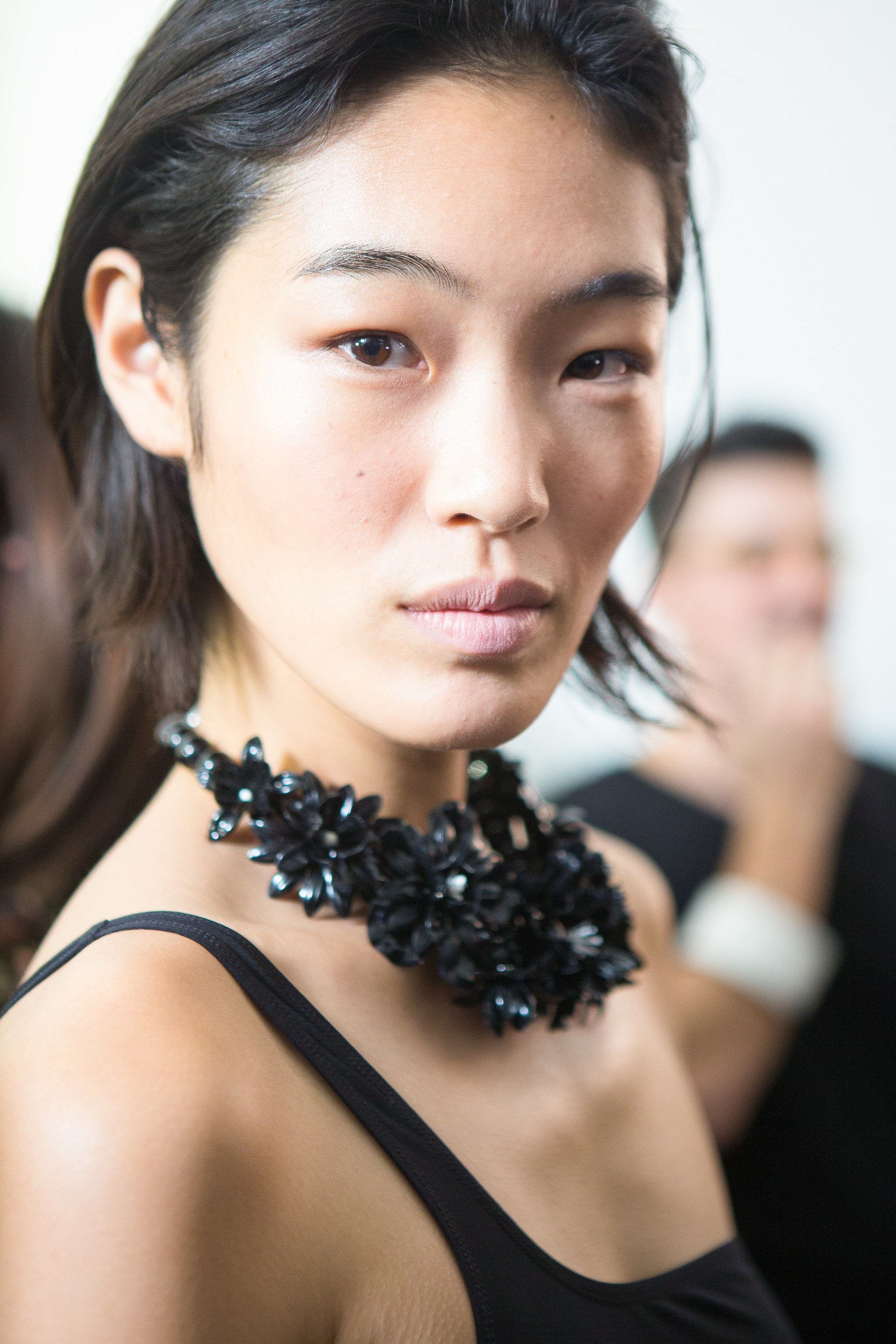 close up shot of woman with slicked back party bob hairstyle, wearing black necklace