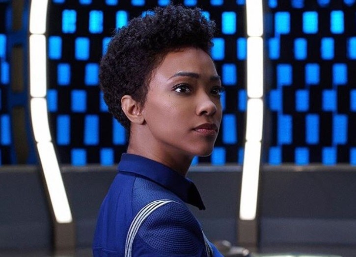 close up shot of sonequa martin-green with short natural curly hair on the set of the star trek discovery, wearing blue suit