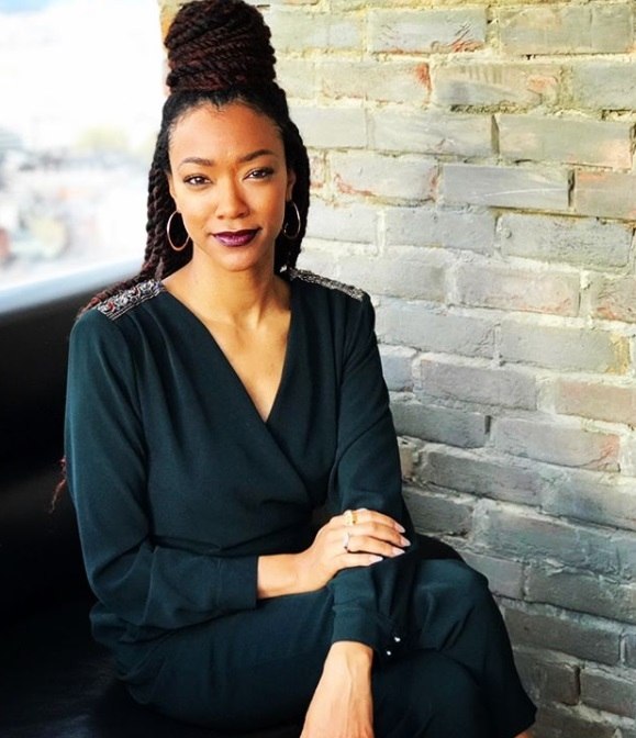 close up shot of sonequa martin-green with box twists half up bun hairstyle, wearing dark green dress