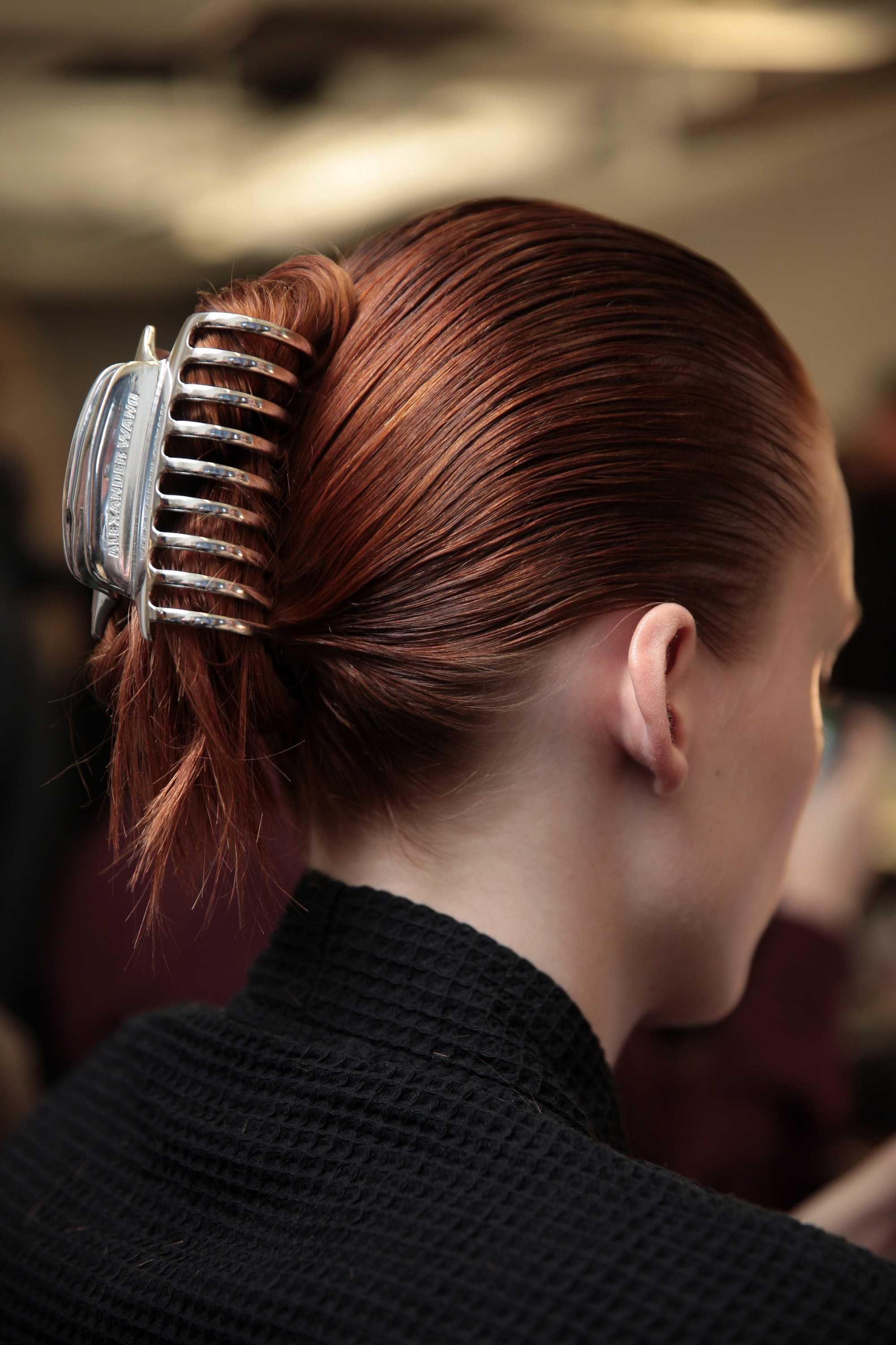 back view of model with auburn hair in updo with hair claw backstage at fashion week