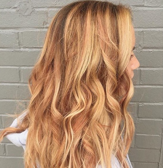 piced cider hair: Side view of strawberry blonde balayage on long wavy hair