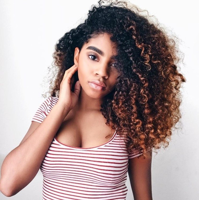natural hair ombre: close up shot of woman with copper ombre curly hairstyle, wearing striped shirt and posing