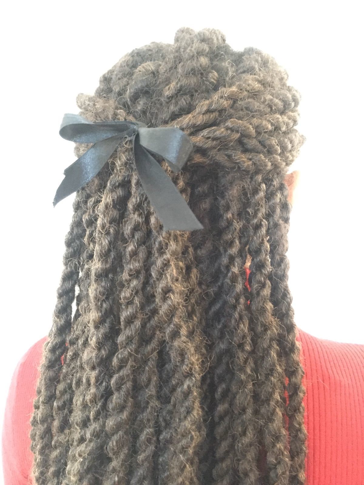 backshot of woman with half up half down marley twist hairstyle that has a bow in it, wearing red jumper