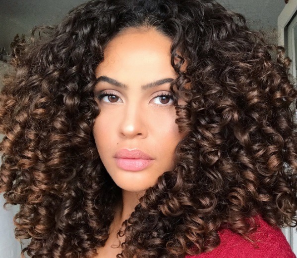 close up shot of woman with chocolate ombre natural hair, wearing red top and subtle makeup