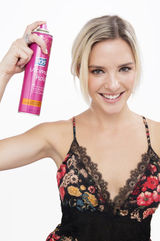 How to do a messy bun with long hair blonde girl smiling at camera with hairspray