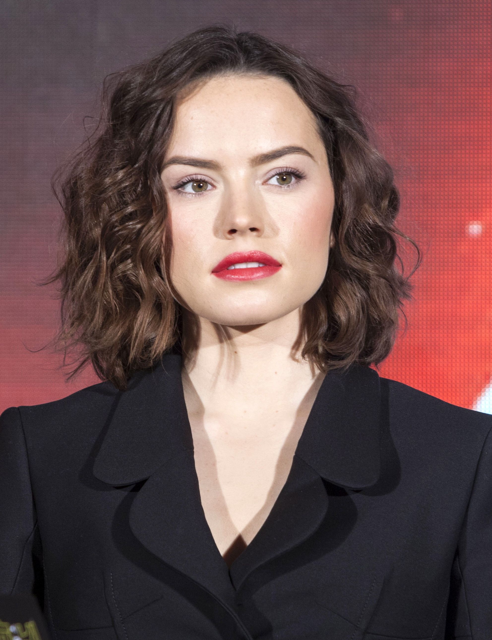 front view of daisy ridley with brown curly shoulder length hair