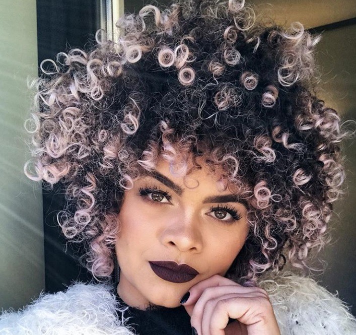 close up shot of woman with pink ombre on natural hair, with purple lipstick and wearing a fluffy jumper