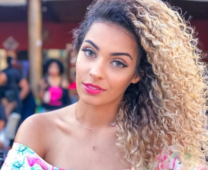 close up shot of woman with curly blonde ombre hairstyle, wearing low cut top and posing outside