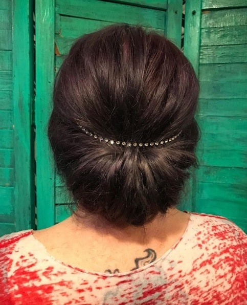 Gibson girl hair: Back view of a woman with dark brown hair in a Gibson roll hairstyle with diamante details