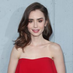 close up shot of lily collins with dark brown hair, fashioned into vintage waves, wearing red dress on red carpet