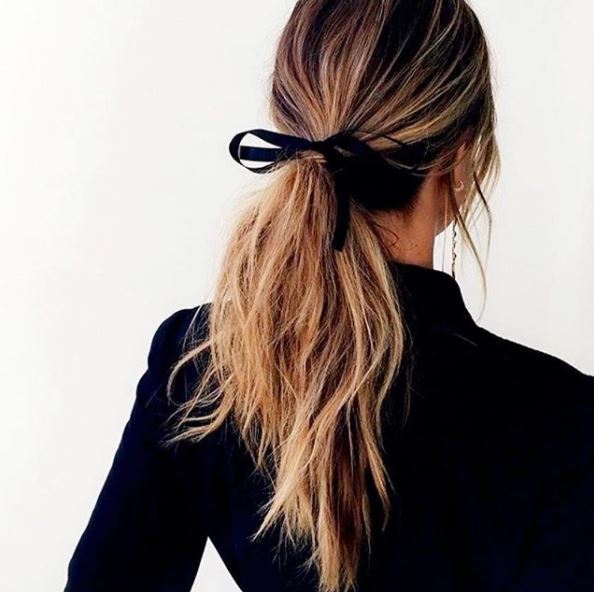 back view of highlighted dirty blonde hair in low ponytail with black ribbon