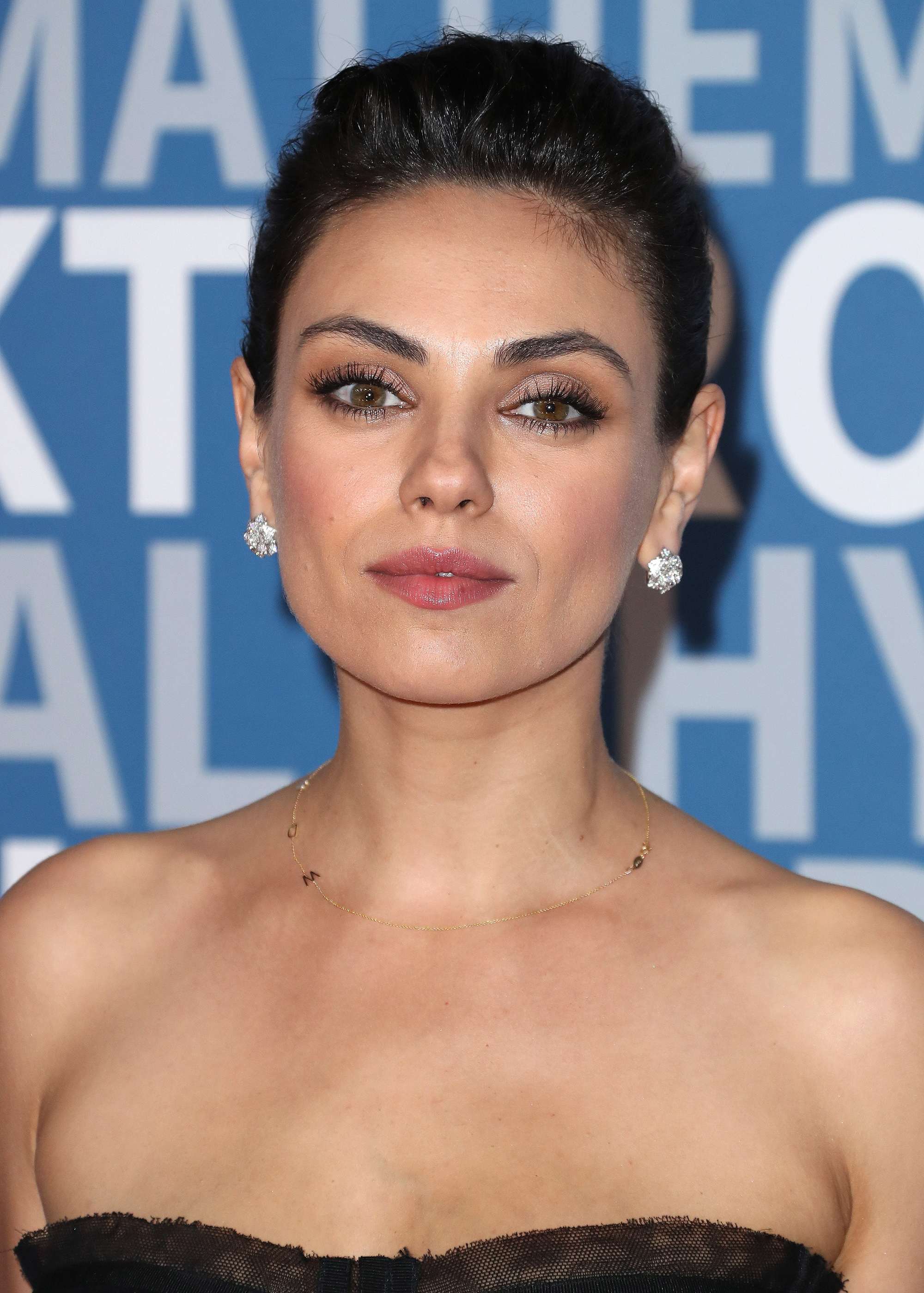 front view of mila kunis with dark brown hair in small quiff updo