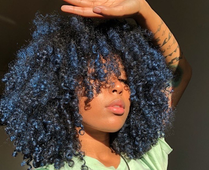 ombre natural hair: close up shot of woman with curly hair with blue ombre hairstyle done