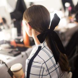 backstage shot at Tory Burch, of model with ribbon in her hair, getting her makeup done