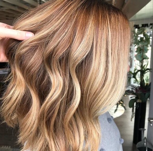 Spiced cider hair: Side view of strawberry golden blonde medium length wavy hair