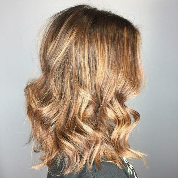 side view of strawberry golden blonde balayage medium length wavy hair