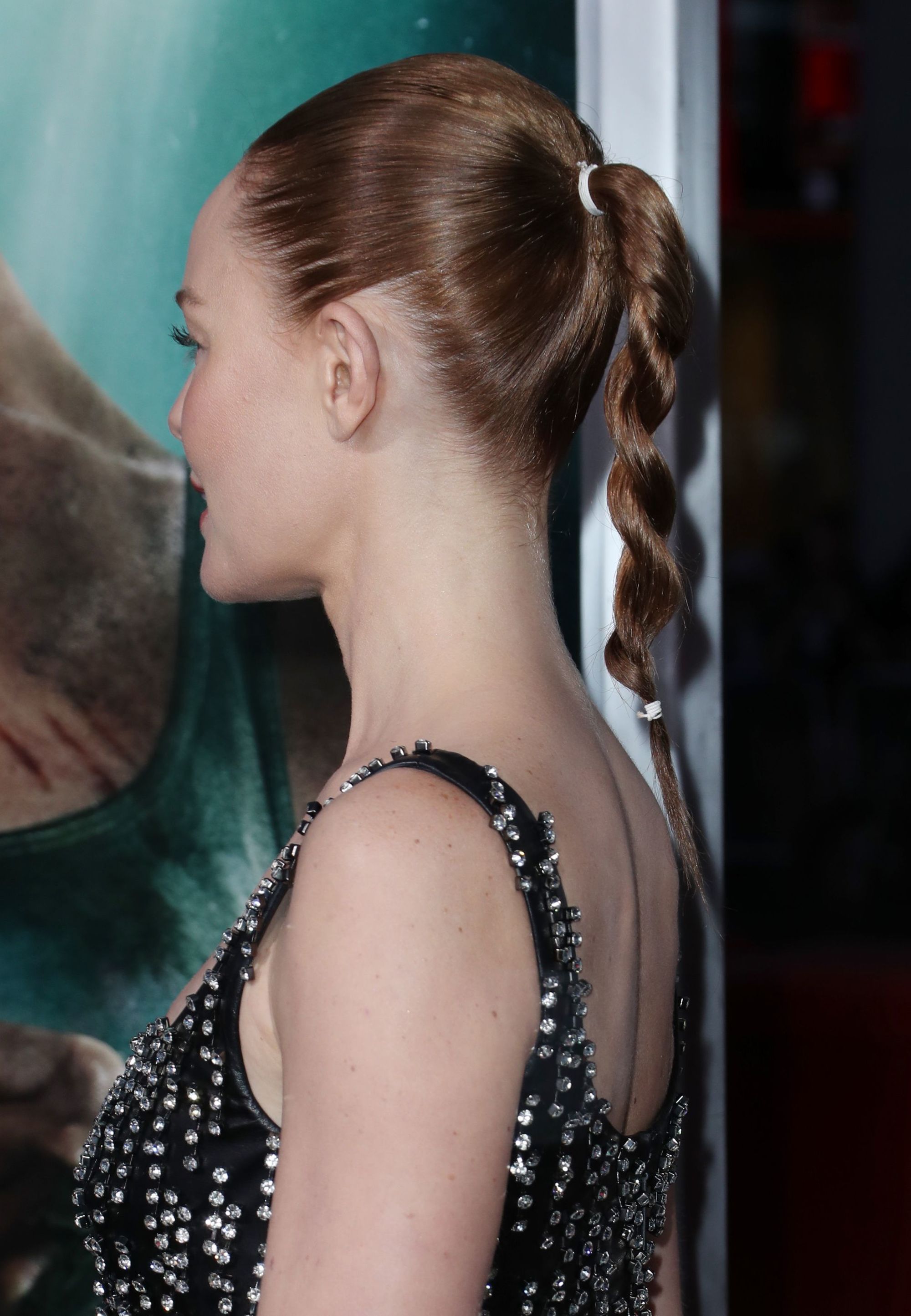 Kate Bosworth with her chestnut brown hair styled into a twisted rope ponytail, wearing a black sparkly dress on the red carpet