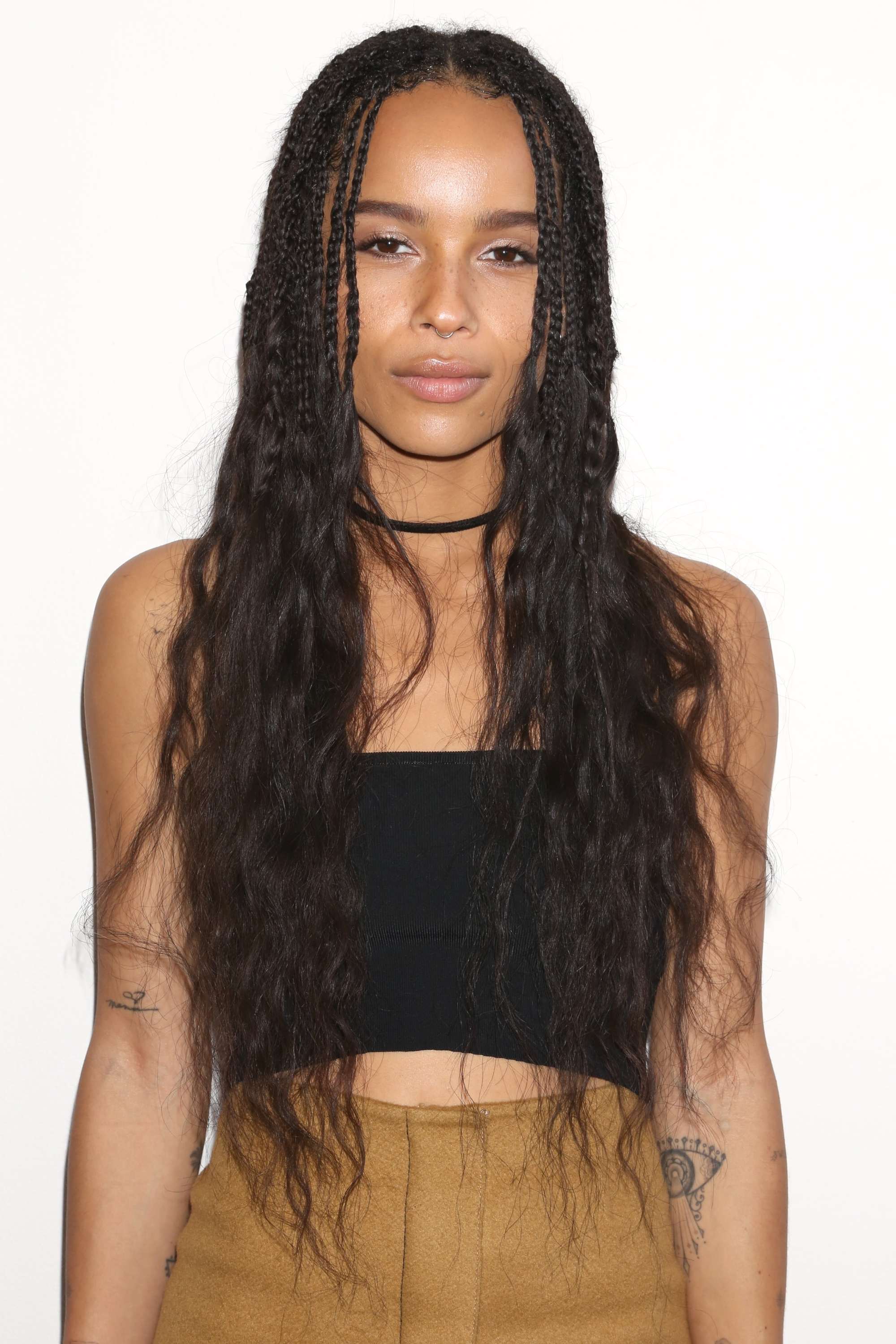 block braids hairstyles: close up shot of zoe kravitz with loose box braids, wearing black top crop and suede skirt