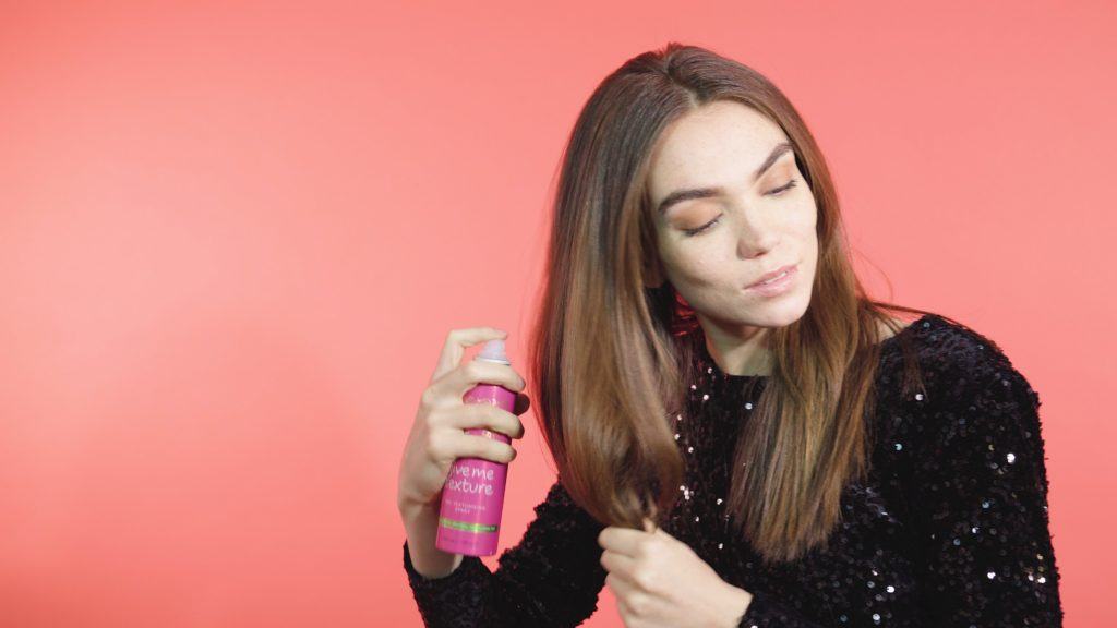Woman with mid-length brunette hair spraying texturising spray