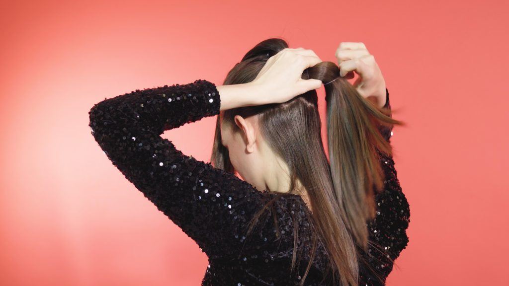 Brunette girl tying a ponytail into a hairband