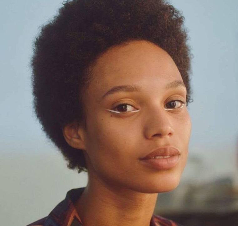 close up shot of afrodita dorado with short tapered afro, wearing minimal makeup and posing for a magazine cover