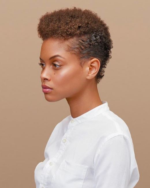 2019 haircut predictions: Woman with golden brown naturally curly short hair styled with a mohawk.