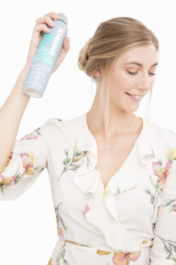 Banana bun hairstyle blonde girl using hairspray