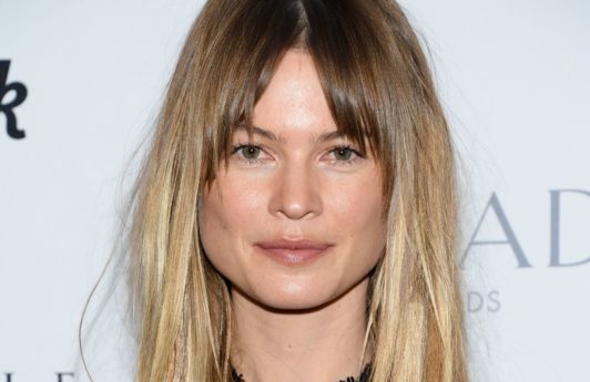 close up shot of behati prinsloo with subtle shadow roots ombre hair with bangs, wearing black dress on the red carpet