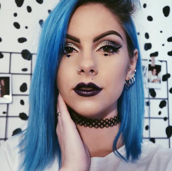 front view of woman with bright blue shoulder length hair and dark roots