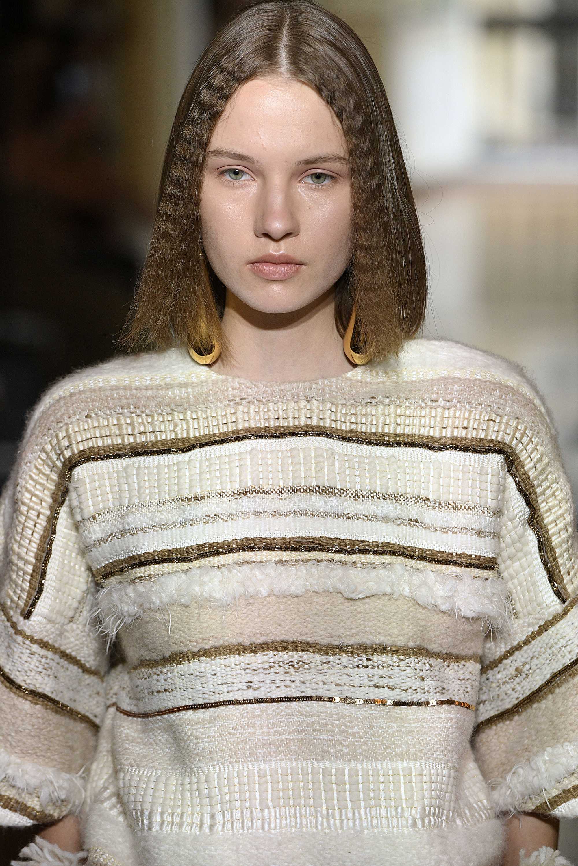 Paris Haute Couture Week fw18: close up shot of model on the christophe josse runway with a light brown, shoulder length bob, complete with crimped accents at the front, wearing sandy shirt and walking on the runway