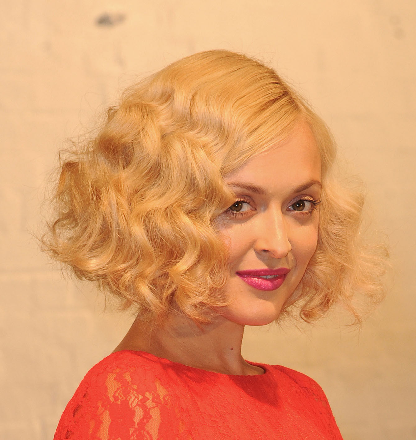 Angled bob: Fearne Cotton with a blonde 1920s inspired wavy angled bob with a side parting, wearing pink lipstick and a red lace dress