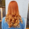 back view of a woman with orange copper ombre long curly hair