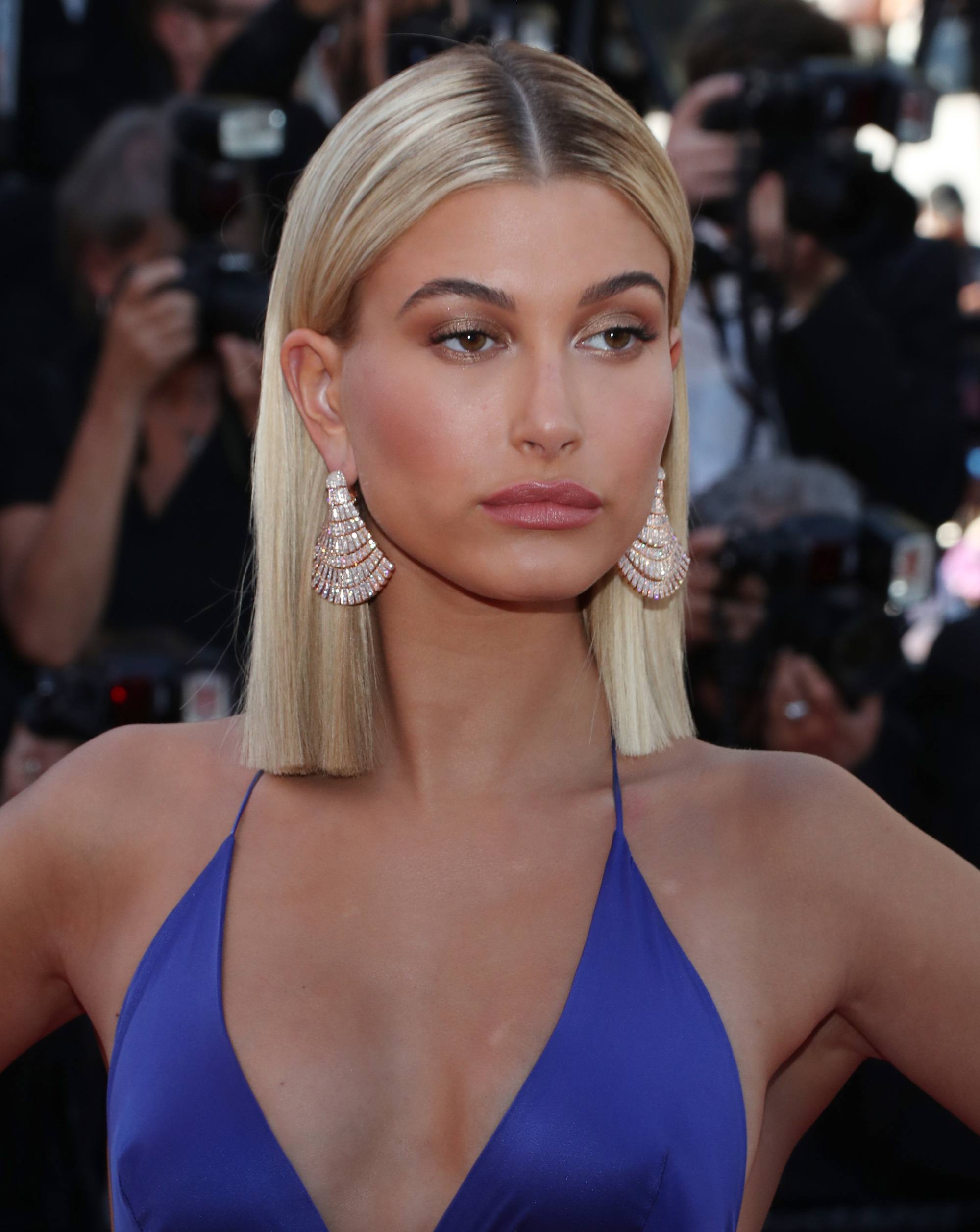 straight short hairstyle: close up shot of hailey baldwin with straight, sleek hair, wearing blue top and posing on the red carpet