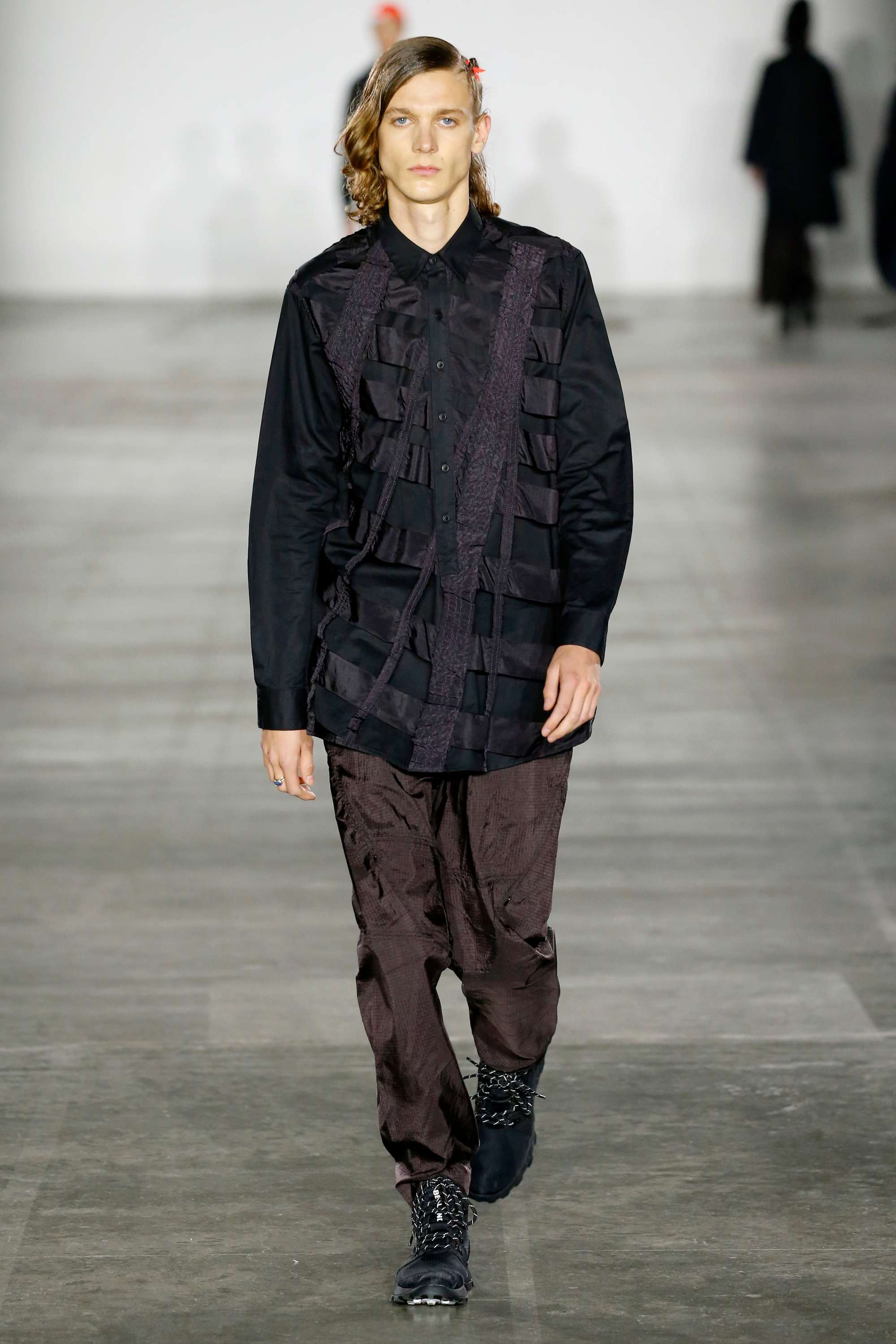 London Fashion Week Men's: Model on Christopher Raeburn runway with blonde wavy shoulder length hair styled with a side braid.