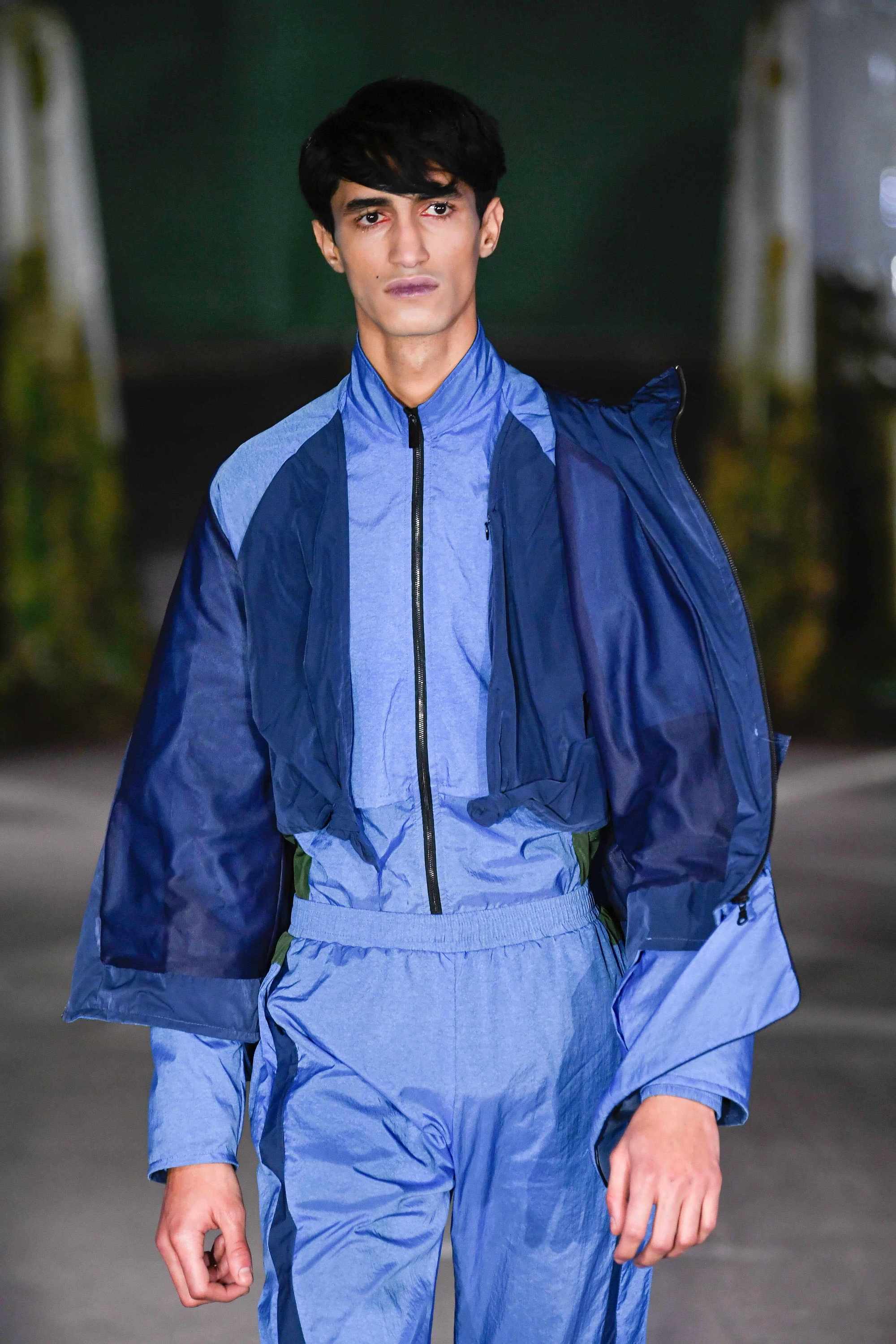 London Fashion Week's Men: Model with dark brown hair with side fringe wearing blue sports wear.