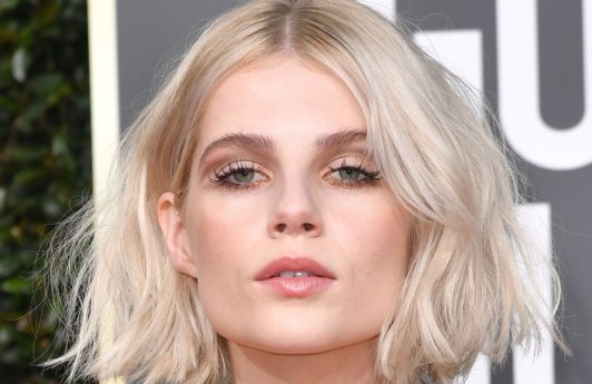 Lucy Boynton with a platinum wavy, beachy bob, wearing a gold dress on the Golden Globes