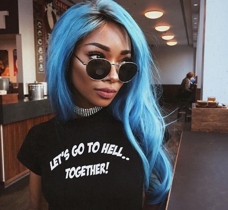 close up shot of woman with blue hair colour, wearing a slogan tee and sunglasses