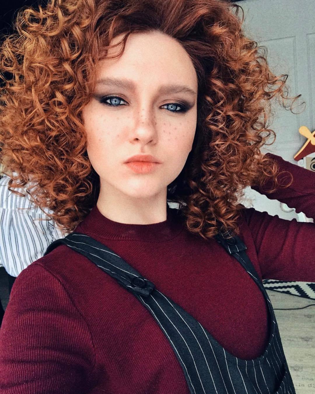 Permed hair care girl with curly ginger ringlets taking a selfie