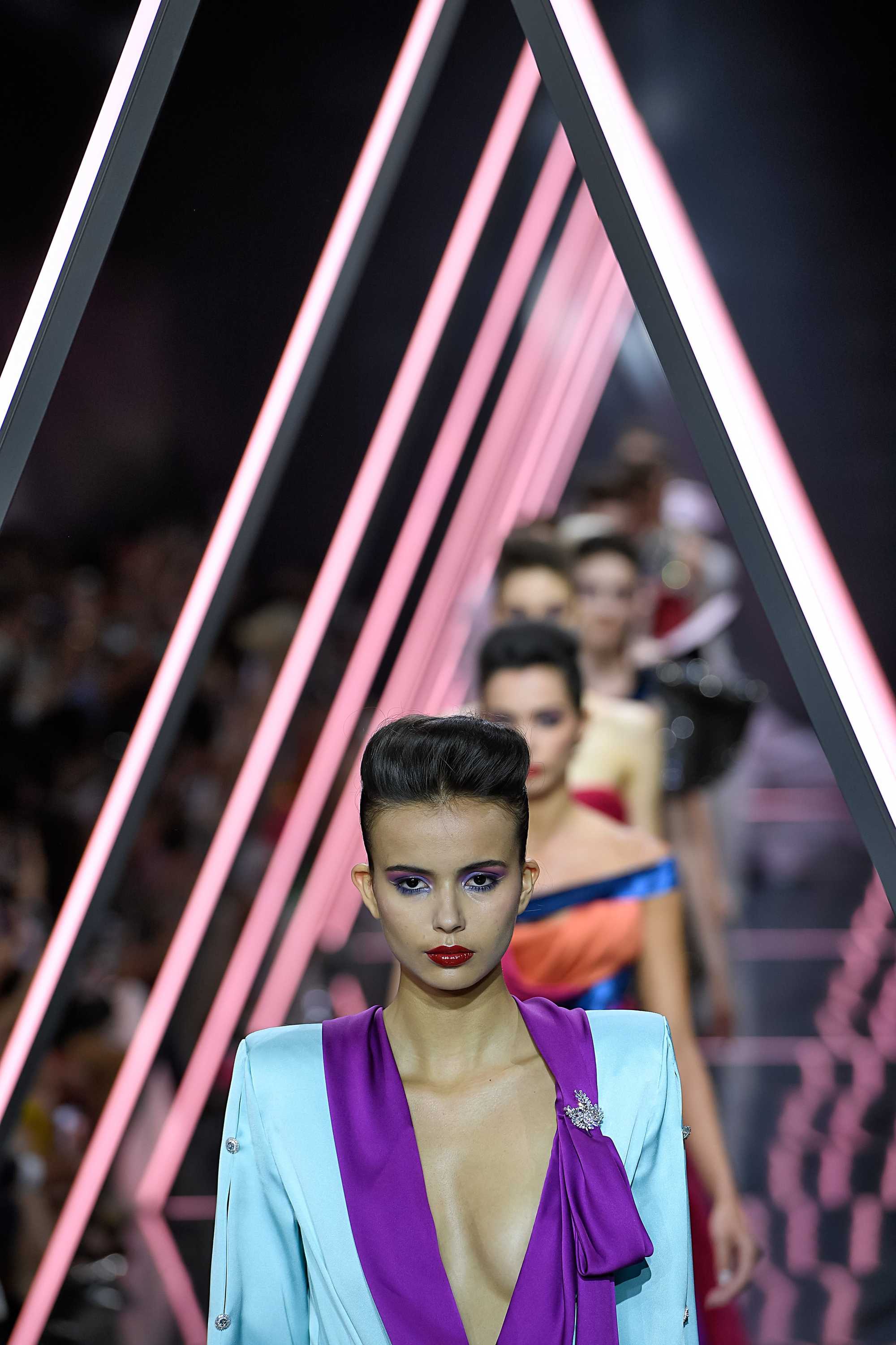 Paris Haute Couture Week fw18: close up shot a woman with short dark brown styled into a voluminous, swept-back quiff, wearing a colourful suit and walking down the ralph russo runway