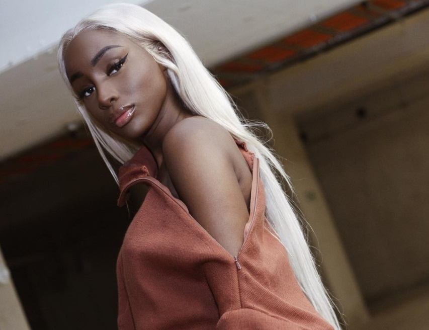 close up shot of woman with silver blonde hair, wearing a open cut jumper and posing