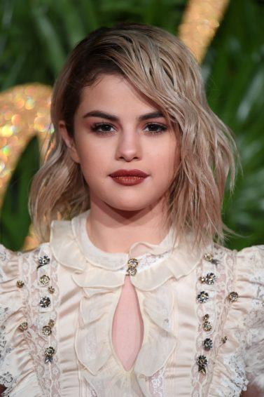 front view of selena gomez with blonde shoulder length hair and dark roots