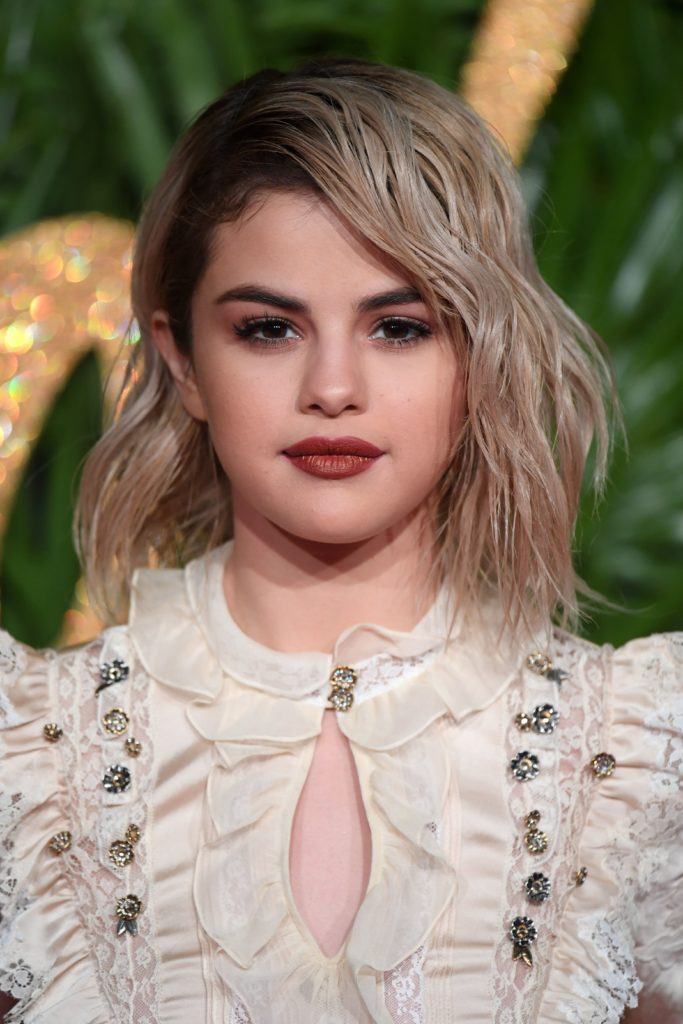 front view of selena gomez with blonde shoulder length hair and dark roots