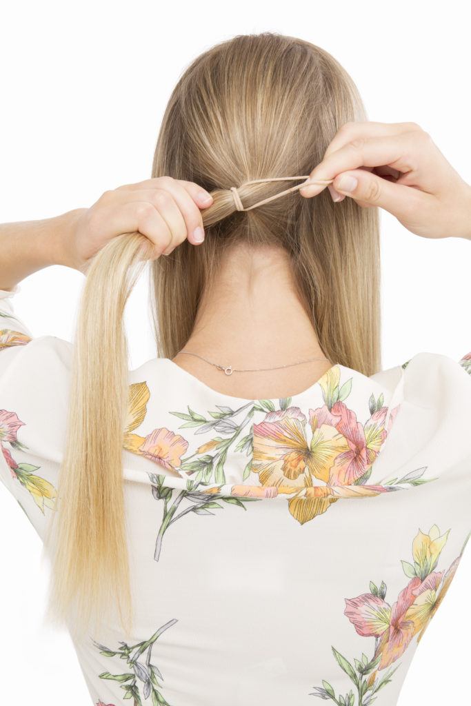 Banana bun tutorial girl with blonde hair tying into a low ponytail