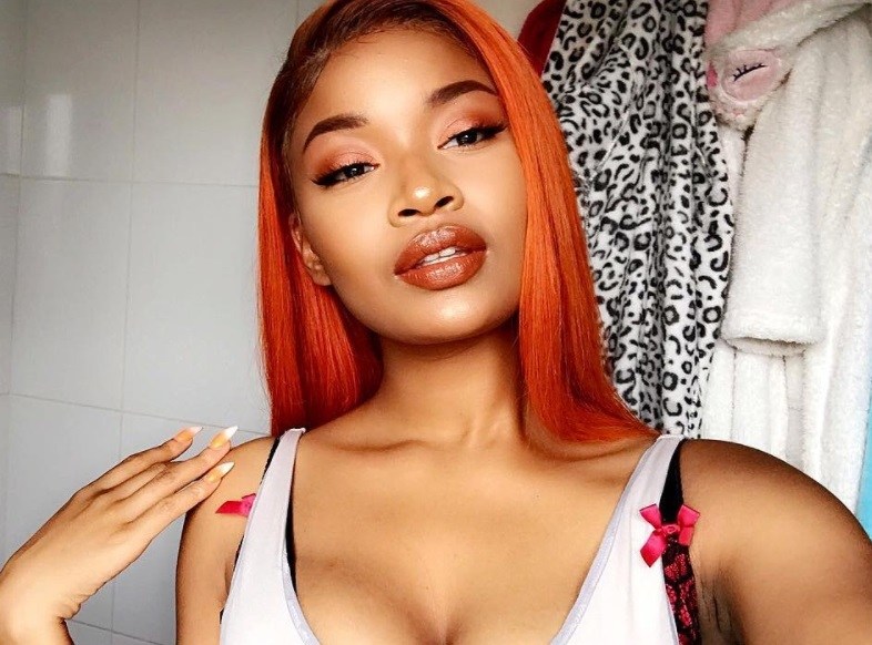 close up shot of black woman with fanta red hair, wearing white top and posing in bathroom