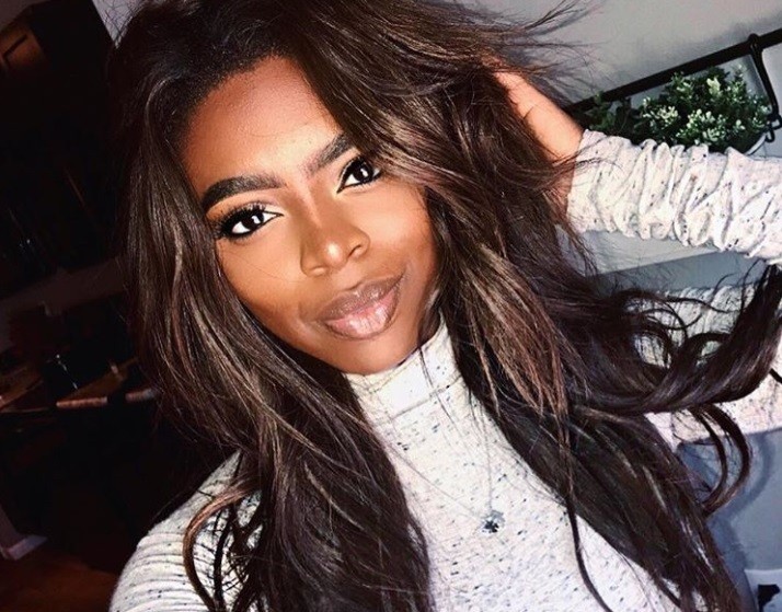close up shot of woman with chocolate brown hair, wearing white turtle neck and posing
