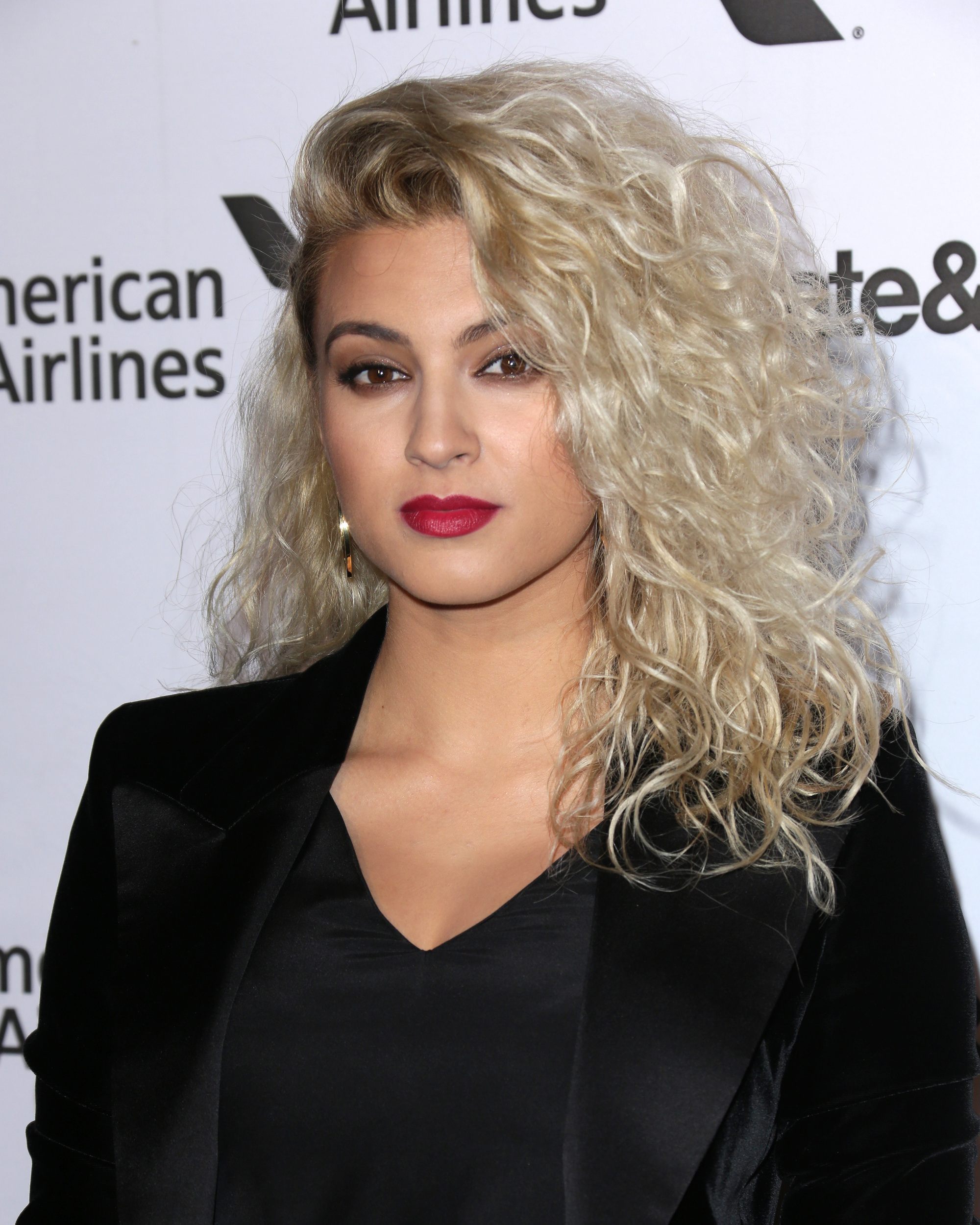 Permed hair care Tori Kelly on the red carpet with blonde voluminous curly hair