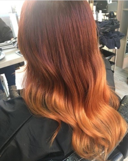 back view of a woman with glossy copper ombre hair