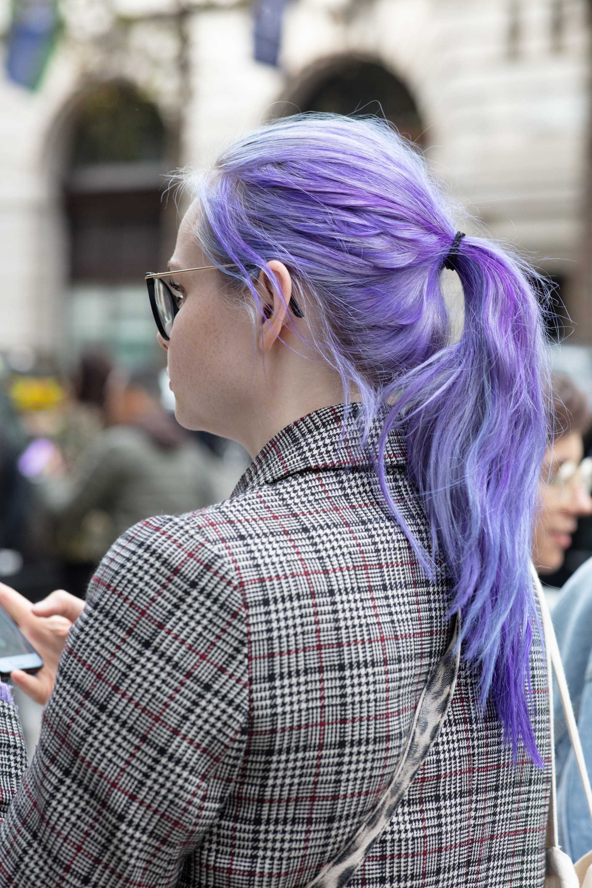 Washing hair after colouring: Rear view of women with long purple hair styled into a ponytail, wearing blazer and posing for an All Things Hair street style shot